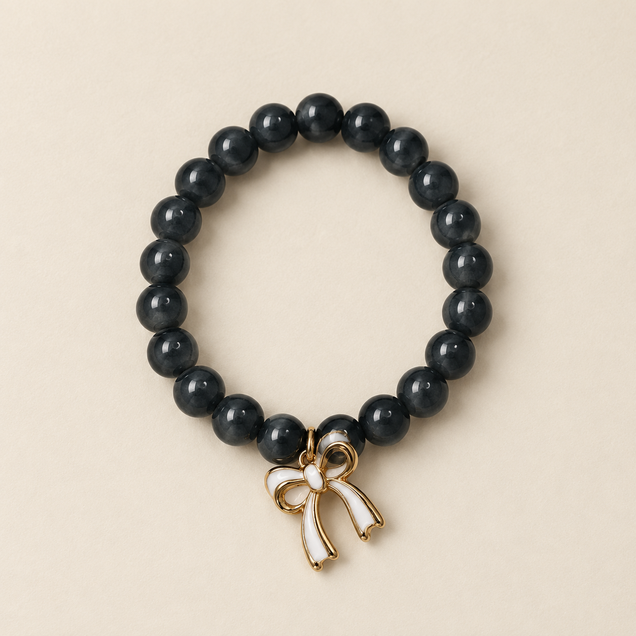 Charcoal beaded bracelet with a gold and white enamel bow charm